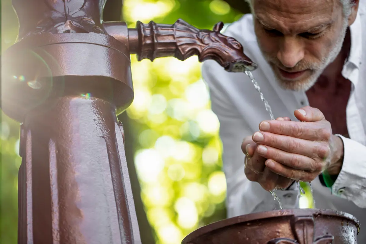 man drinking water from a spring
