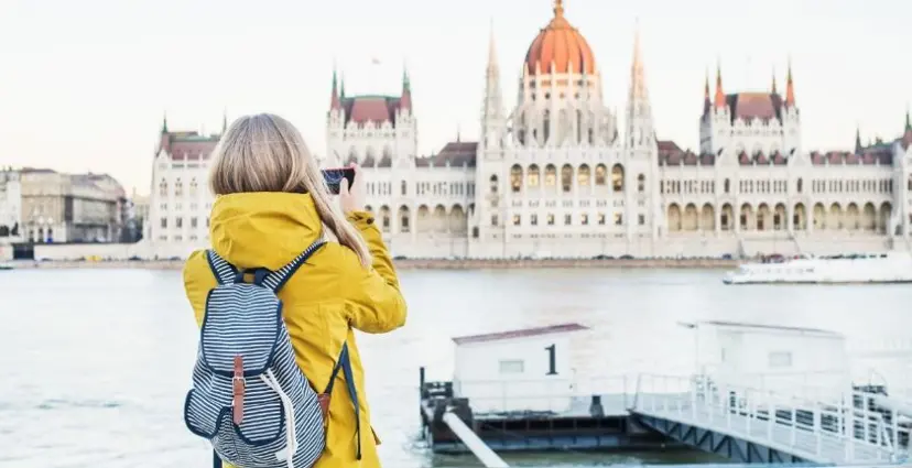 O femeie fotografiază clădirea Parlamentului din Budapesta de peste râu