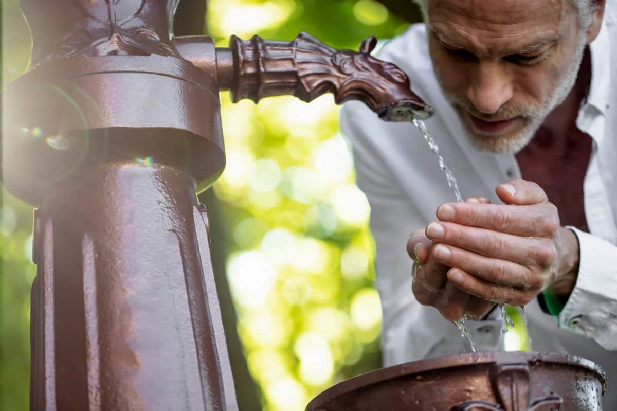 man drinking water from a spring