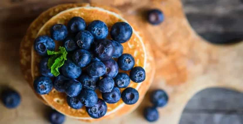 Pancakes with blueberries on a wooden plate